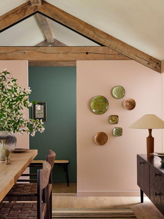 Helles Vintage Wohnzimmer mit Holzbalken, Retro-Möbeln, Deko-Tellern an rosa Wand