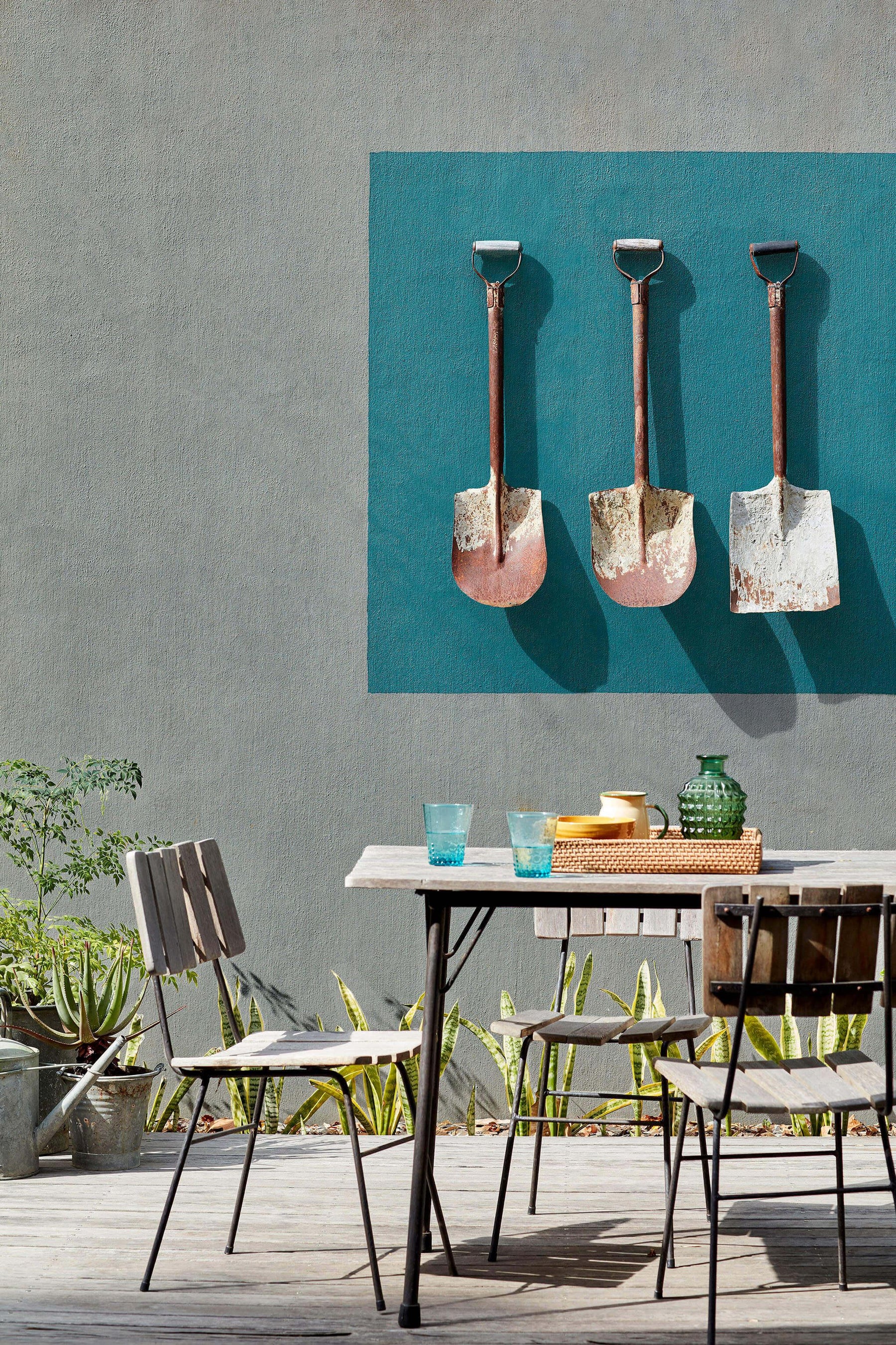 Vintage Gartenmöbel und dekorative alte Schaufeln vor Wand mit Little Greene Farbe, Outdoor-Szene