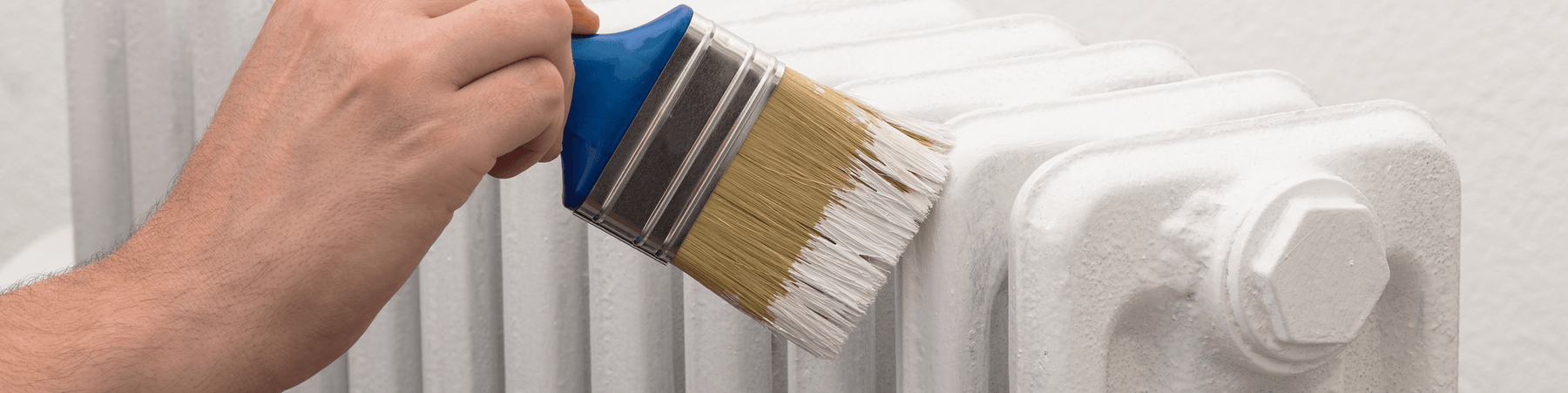 Hand streicht weißen Heizkörper mit Pinsel, nachhaltiges Upcycling von Vintage Kontor